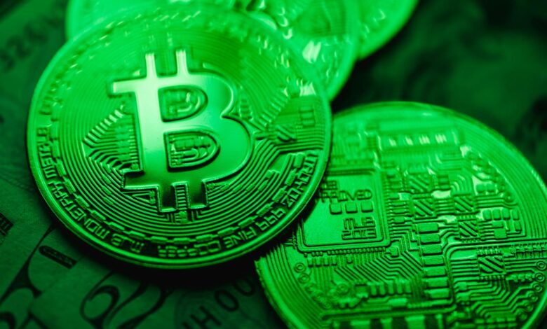 Close-up of green-illuminated Bitcoin coins representing digital currency and blockchain technology.