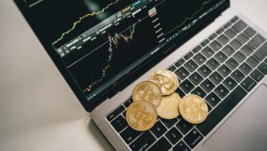 Golden bitcoin coins placed on a laptop keyboard with trading chart displayed on the screen.