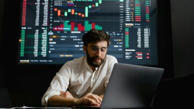 Male analyst studies cryptocurrency trends at a workstation with multiple displays showing market data.