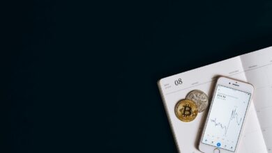 Smartphone displaying cryptocurrency data next to Bitcoin on a calendar offers finance and technology insights.