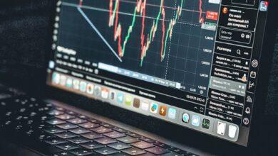 Laptop displays a stock market trading chart.