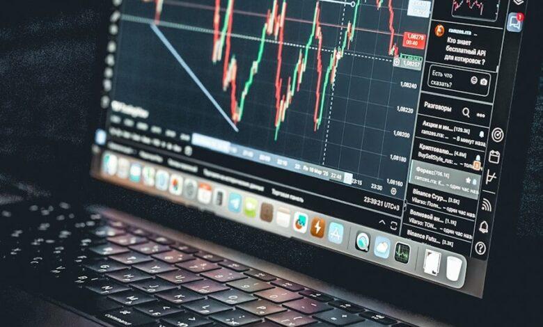 Laptop displays a stock market trading chart.