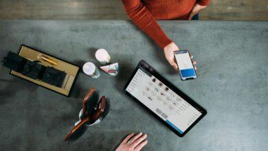 person holding smartphone beside tablet computer