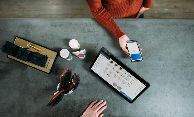 person holding smartphone beside tablet computer